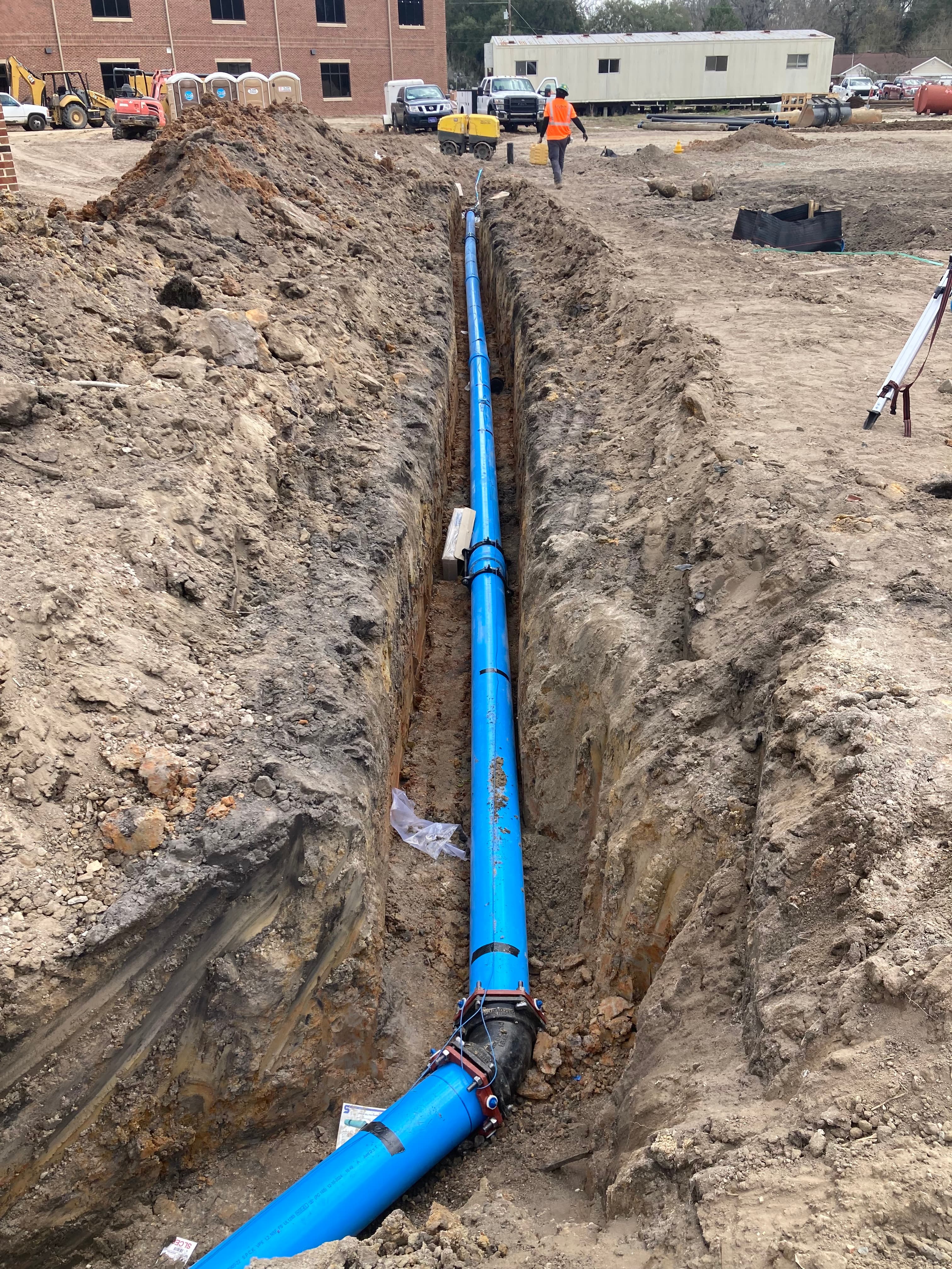 Blue PVC water main laid in an open trench on a commercial site