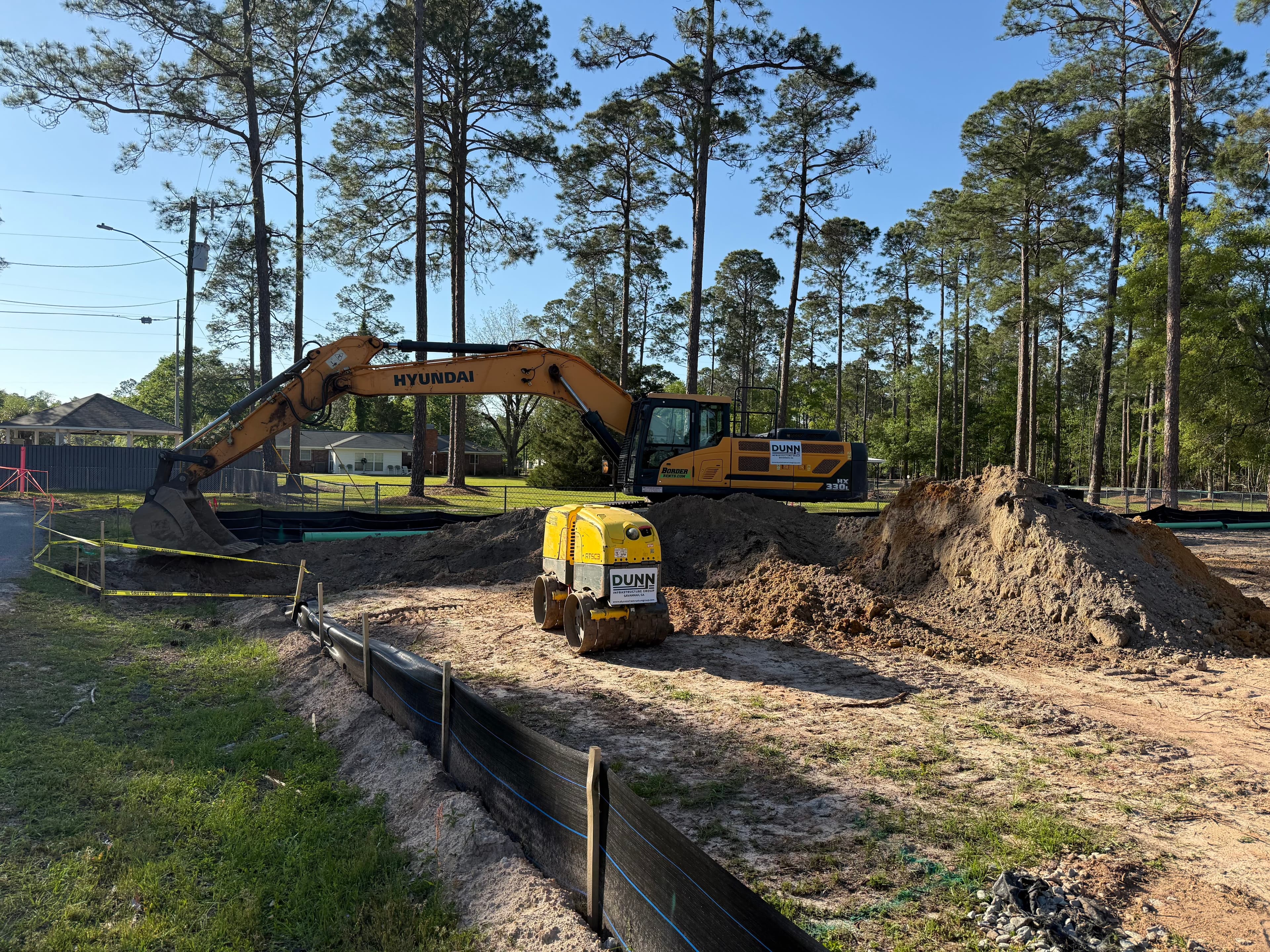 Dunn Infrastructure Group excavator and compaction equipment on an active subdivision utility site